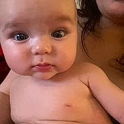 Lyla is registered to the contest to win money with this photo: baby, infant, child, adult, portrait, close_up, face, eyes, wide_eyed, serious, indoor, warm_lighting, candid, sitting, bare_chested, diaper, blanket, caregiver, selfie, family