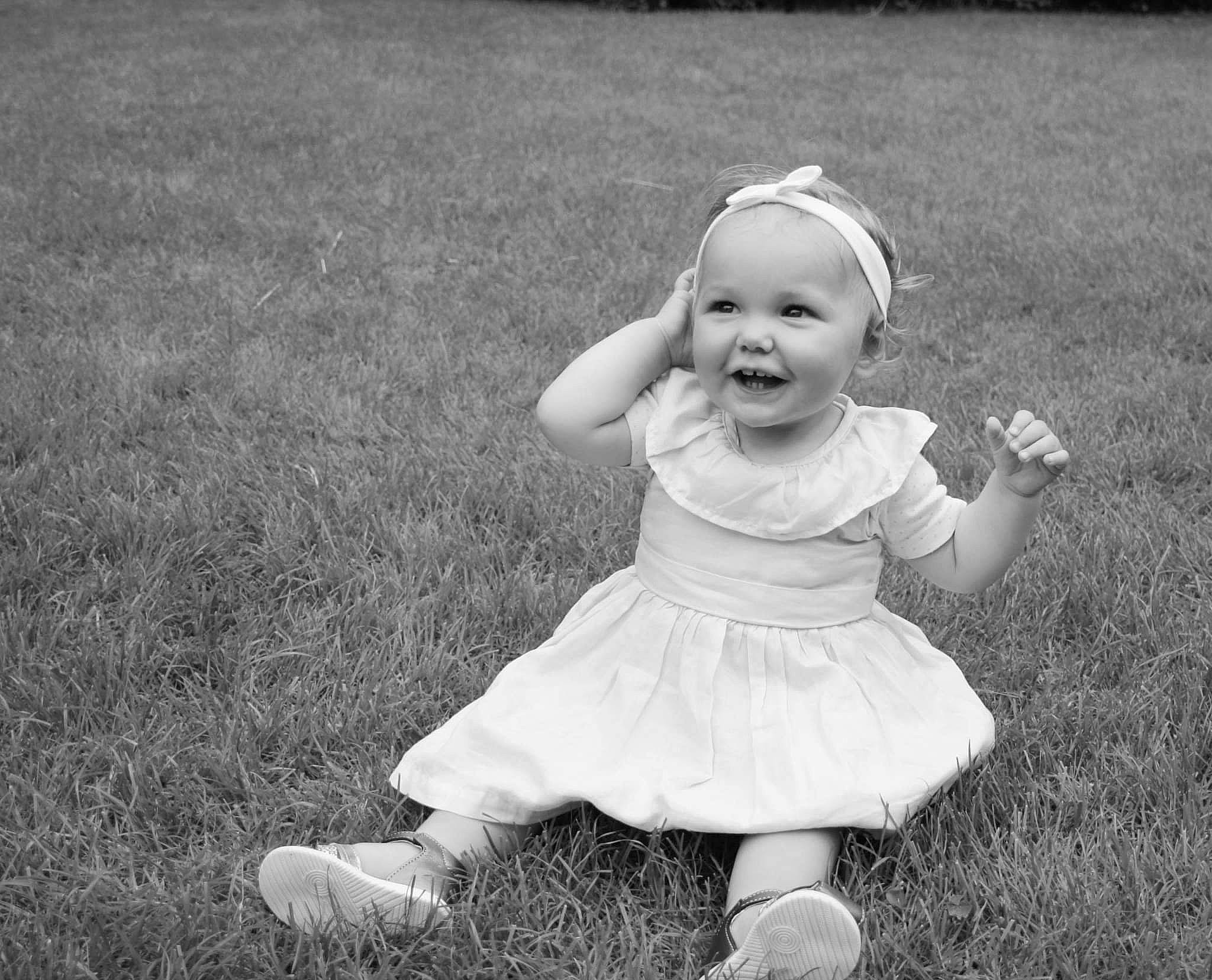 Aria participe au concours pour gagner de l'argent avec cette photo : baby, baby_toddler_clothing, child, dress, flash_photography, fun, gesture, grass, grass_family, grassland, happy, iris, joy, monochrome, people_in_nature, person, plant, skin, smile, standing