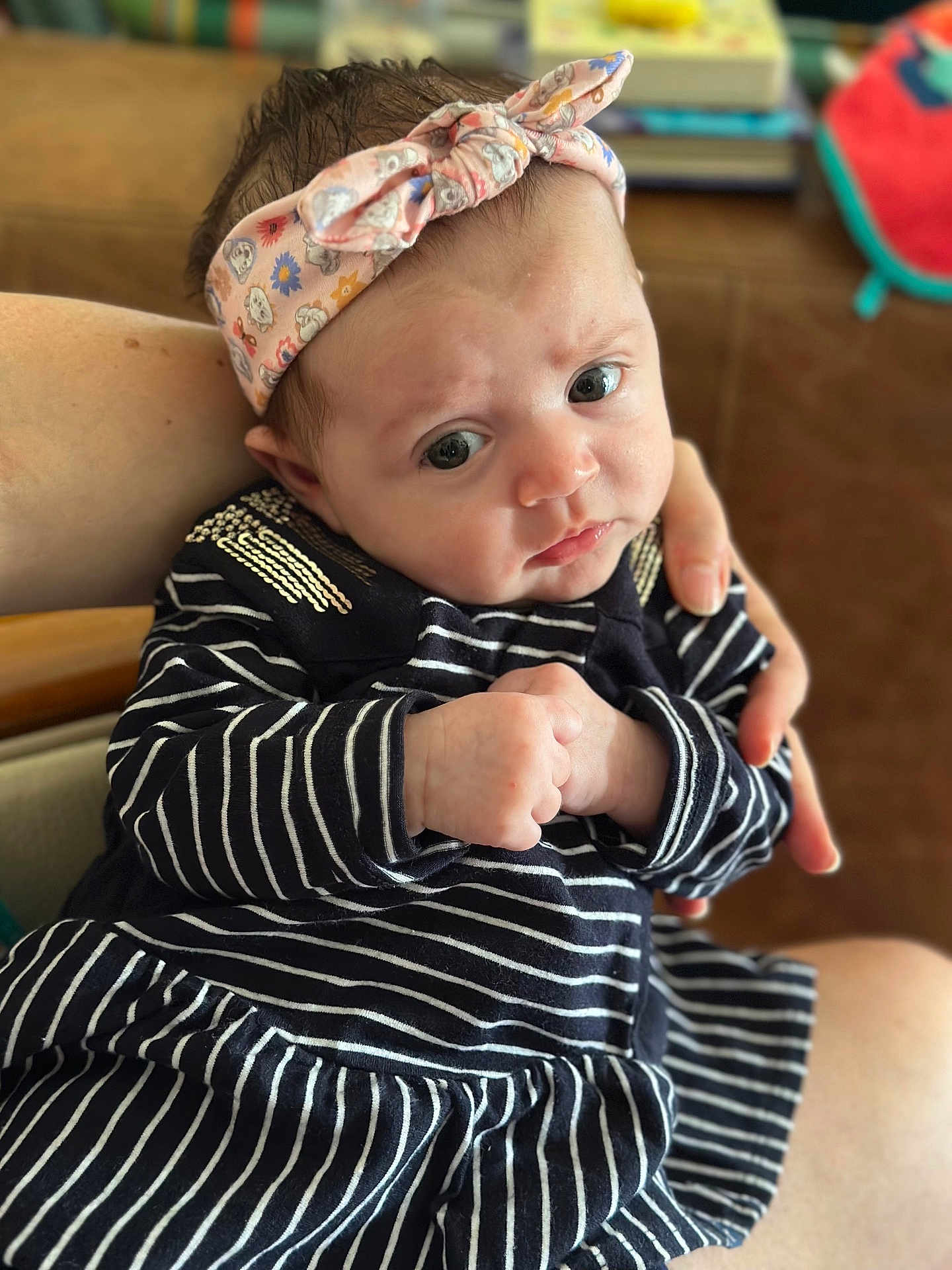 Rose participe au concours pour gagner de l'argent avec cette photo : baby, infant, headband, striped_clothing, hand, face, eyes, person, indoor, blurred_background, skin, cute, child, newborn, holding, sitting, expression, clothing, soft_light, portrait
