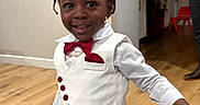 Joab joined the competition — help win amazing prizes! child, toddler, smiling, red_pants, white_vest, bow_tie, indoor, home, kitchen, carpet, wood_floor, person, happy, fashion, cute, playful, bracelet, black_shoes, cabinet, appliance