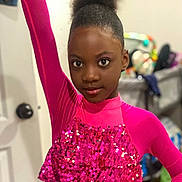 Jemima is registered to the contest to win money with this photo: child, girl, pink_clothing, sequins, posing, indoor, portrait, afro_hair, confident, young, fashion, sparkle, long_sleeve, raised_arm, expression, person, room, door, blurred_background, standing