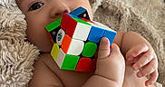 Huckleberry joined the competition — help win amazing prizes! baby, blanket, chewing, child, closeup, couch, curious, cute, face, fingers, hand, indoor, infant, playful, relaxed, rubiks_cube, skin, soft_texture, toy, young