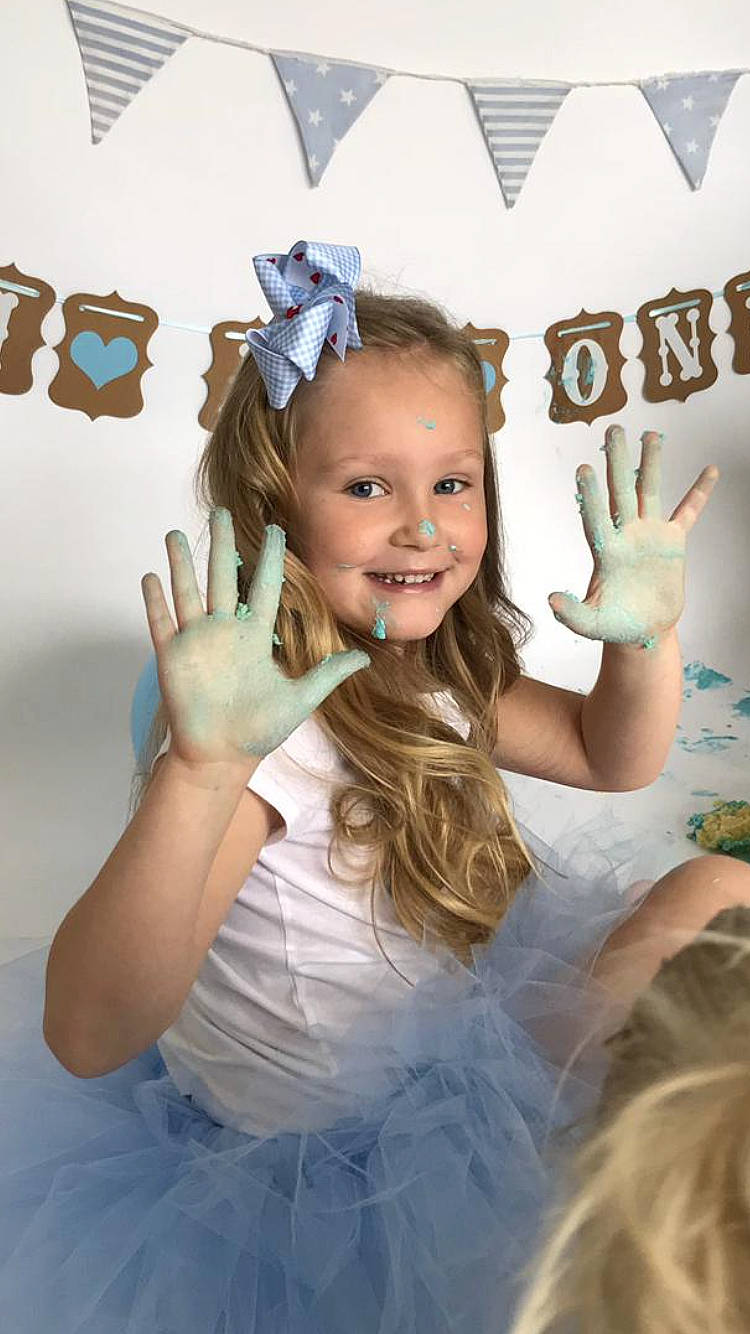 Dolly is registered to the contest to win money with this photo: blue, child, costume, fun, girl, hair_accessory, happiness, headpiece, joy, party_hat, person, product, smile, toddler