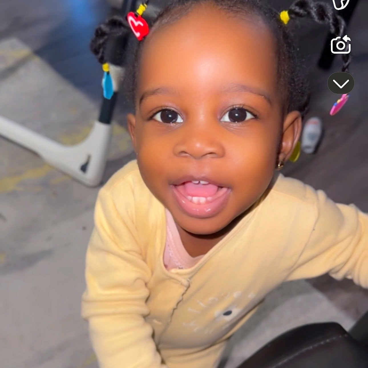 Kayla a rejoint le concours — aidez-le/la à gagner de superbes lots ! baby, beads, braided_hair, child, closeup, cute, face, floor, furniture, hand, happy, indoor, joyful, person, playful, portrait, smiling, toddler, yellow_clothing, young_child