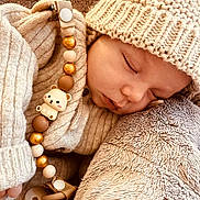 Lio participe au concours pour gagner de l'argent avec cette photo : baby, sleeping, knit_hat, knit_sweater, pacifier, beads, bear_charm, plush_blanket, cozy, soft_texture, infant, cute, child, resting, warm_clothing, closeup, portrait, peaceful, indoors, comfort