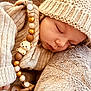 baby, sleeping, knit_hat, knit_sweater, pacifier, beads, bear_charm, plush_blanket, cozy, soft_texture, infant, cute, child, resting, warm_clothing, closeup, portrait, peaceful, indoors, comfort