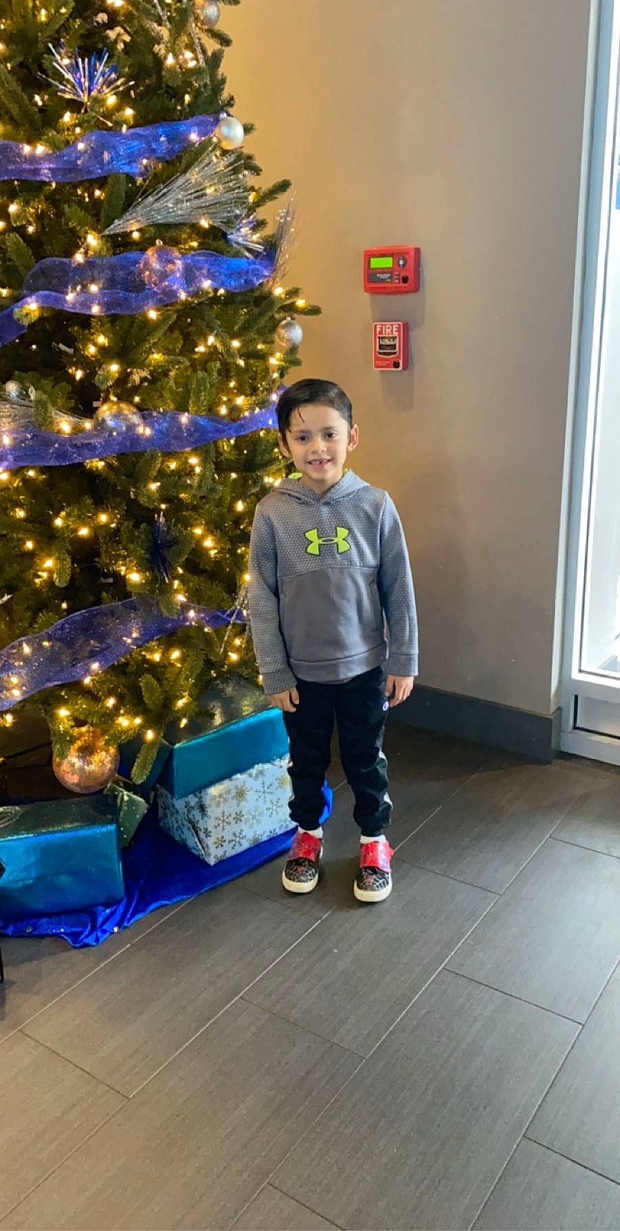 Jaime is registered to the contest to win money with this photo: child, christmas, christmas_decoration, christmas_eve, christmas_ornament, christmas_tree, event, fir, footwear, fun, holiday, interior_design, joy, person, pine_family, plant, standing, toddler, tree