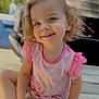 toddler, child, smiling, curly_hair, pink_clothing, outdoor, wooden_deck, portrait, happy, face, eyes, sitting, cute, young_child, sunlight, daylight, casual, person, baby, innocence