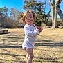 toddler, child, barefoot, onesie, outdoor, grass, sunny, tree, blue_sky, nature, playful, face, hair, leaves, twigs, standing, daylight, smiling, cute, young_child