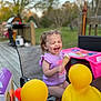toddler, child, ice_cream, purple_shirt, laughing, outdoor, deck, rubber_duck, yellow, plastic_toy, table, chair, play_table, grass, trees, smiling, summer, happy, person, fun