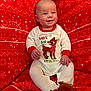 Cooper is registered to the contest to win money with this photo: baby, child, christmas, cozy, cute, face, festive, footed_pajamas, happy, holiday_clothing, indoors, infant, onesie, plush_slippers, portrait, red_blanket, reindeer, sitting, smiling, winter