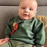 Loann a rejoint le concours — aidez-le/la à gagner de superbes lots ! baby, child, face, person, couch, clothing, green_sweater, pants, hand, indoor, portrait, cute, seated, soft_furniture, home, expression, skin, eyes, sitting, comfort
