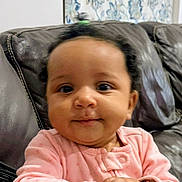 Sade Zanarielle is registered to the contest to win money with this photo: baby, infant, child, pink_clothing, hands, bracelets, couch, leather, blanket, pattern, curtain, floral, indoors, portrait, smiling, cute, young_child, face, person, seated