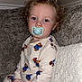toddler, child, pajamas, paddington_bear, pacifier, curly_hair, blue_eyes, couch, blanket, indoor, person, sitting, clothing, comfort, soft_texture, home, relaxed, cute, baby, portrait
