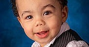 Jayden is registered to the contest to win money with this photo: toddler, child, curly_hair, vest, white_shirt, portrait, smiling, face, eyes, cheeks, background, studio, fashion, cute, person, head, expression, formal, indoors, young_child