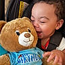 Jayden is registered to the contest to win money with this photo: toddler, child, smiling, happy, plush_toy, teddy_bear, birthday_shirt, car_seat, curly_hair, clothing, baby, cuddling, cute, toy, person, infant, seatbelt, joy, portrait, indoor