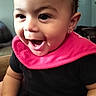 baby, child, infant, smiling, laughing, portrait, close_up, face, eyes, open_mouth, pink_bib, black_clothing, earring, sitting, indoors, home, couch, happy, adorable, photography