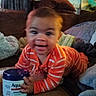 Armani joined the competition — help win amazing prizes! baby, child, infant, smiling, crawling, sitting, portrait, face, orange_clothing, striped_shirt, couch, sofa, pillows, blanket, living_room, indoors, container, cream, household, photography