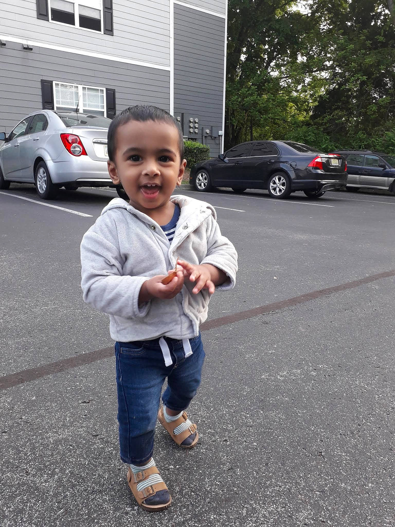 Tufayl joined the competition — help win amazing prizes! asphalt, building, car, gesture, hand, land_vehicle, motor_vehicle, parking, person, road, road_surface, shoe, sidewalk, smile, tire, toddler, tree, vehicle, vehicle_door, wheel