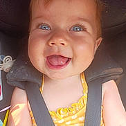 Athénays participe au concours pour gagner de l'argent avec cette photo : baby, child, smiling, blue_eyes, car_seat, seatbelt, yellow_clothing, heart_pattern, happy, cute, face, infant, skin, person, head, mouth_open, tongue_out, sunlight, hand, closeup