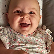 Louise participe au concours pour gagner de l'argent avec cette photo : baby, smiling, infant, happy, face, portrait, child, clothing, floral_pattern, cute, skin, hand, lying_down, indoors, soft_light, background, expression, closeup, person, joy