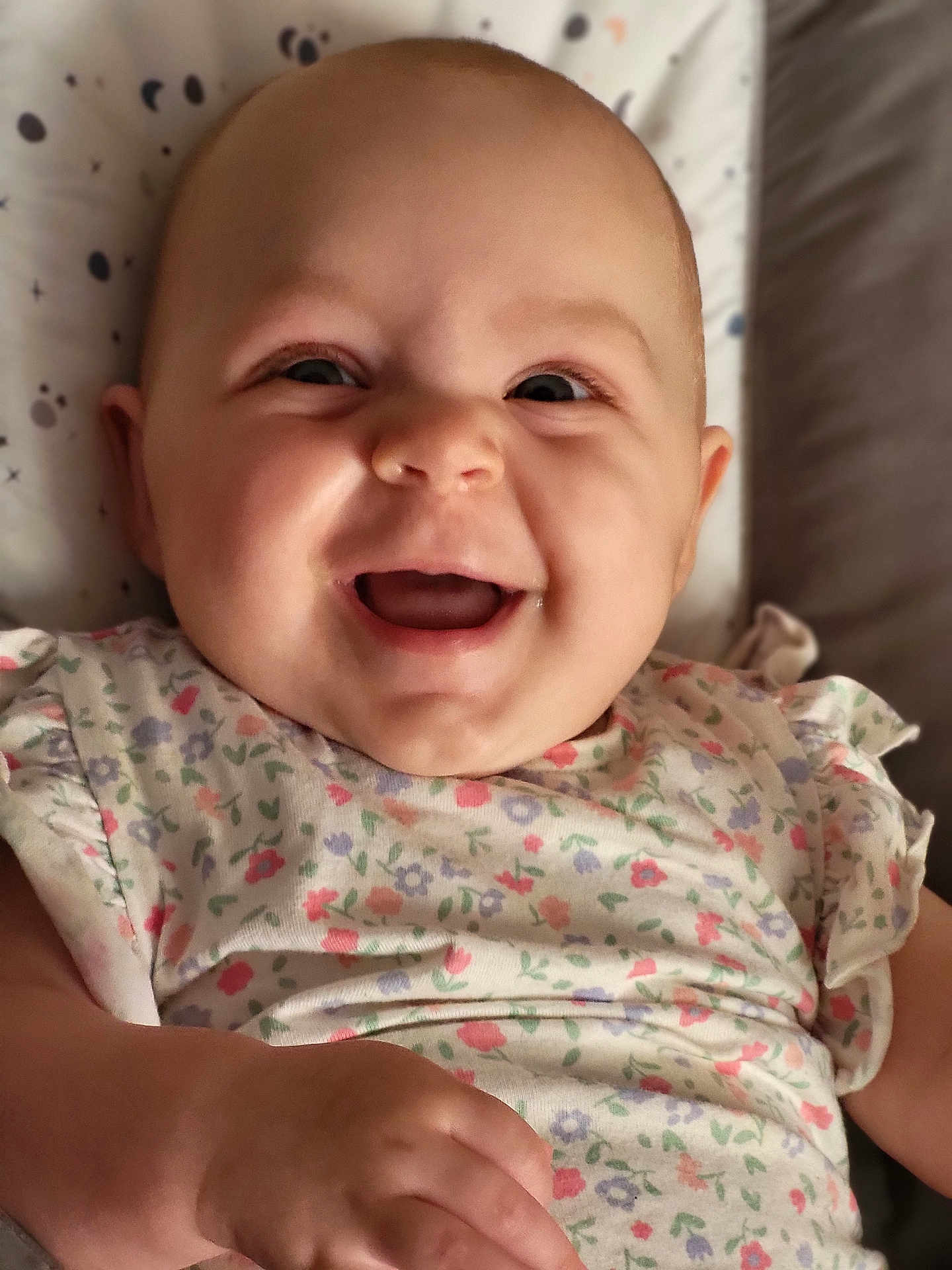 Louise participe au concours pour gagner de l'argent avec cette photo : baby, smiling, infant, happy, face, portrait, child, clothing, floral_pattern, cute, skin, hand, lying_down, indoors, soft_light, background, expression, closeup, person, joy