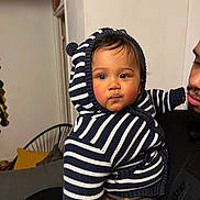 Eliam a rejoint le concours — aidez-le/la à gagner de superbes lots ! baby, child, striped_hoodie, hood, indoor, person, face, cute, cozy, holding, adult, couch, pillow, curious, beard, black_jacket, knitwear, warm_clothing, portrait, home