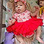 Amanda is registered to the contest to win money with this photo: baby, infant, girl, red_tutu, headband_bow, onesie, cherry_pattern, plush_frog, stuffed_doll, purple_toy, crib, crib_sheet, handprints, blanket, cute, portrait, legs, arms, face, soft_toys