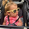 child, toddler, baby, stroller, sunglasses, pink_outfit, blonde_hair, ponytails, portrait, outdoor, seated, harness, safety_straps, fashion, cute, looking_away, plush_toy, sunlight, vehicle, closeup