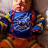 baby, child, firefighter_costume, blue_shirt, orange_pants, infant, cute, soft_blanket, portrait, young_child, costume, bright_colors, face, hand, expression, laying_down, indoors, clothing, person, baby_face