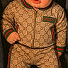 Maverick is registered to the contest to win money with this photo: baby, child, gucci, tracksuit, sneakers, fashion, clothing, footwear, person, portrait, cute, seated, car_seat, young_child, looking_at_camera, face, eyes, hands, expression, indoor