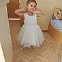 casual, child, door, flooring, footwear, furniture, girl, happy, headband, home, indoor, light, person, playful, portrait, pose, smiling, white_dress, wooden_floor, young_child