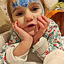 blue, casual_clothing, child, close_up, curious, cute, expression, eyes, face, face_paint, floral_pattern, hands, indoor, jacket, playful, portrait, resting, skin, snowflake, young_child