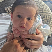 Hunter is registered to the contest to win money with this photo: baby, child, hands, blanket, cushion, indoor, portrait, face, expression, curious, person, holding, closeup, cozy, furniture, soft_light, young, skin, hair, comfort
