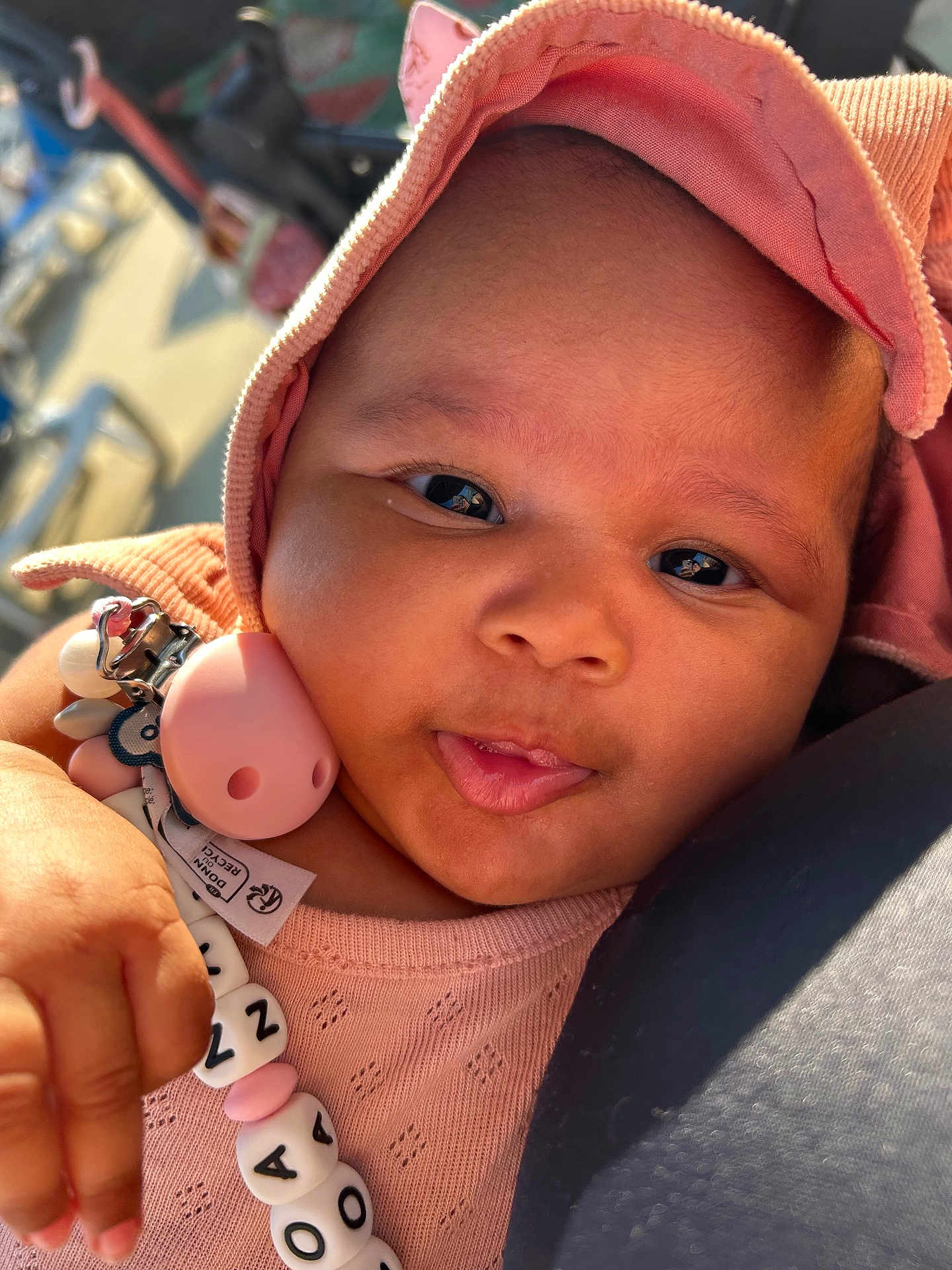 Loa Nawi participe au concours pour gagner de l'argent avec cette photo : baby, child, face, hand, pacifier, beads, hood, clothing, pink, closeup, portrait, cute, infant, skin, expression, warm_light, outdoor, person, young_child, holding