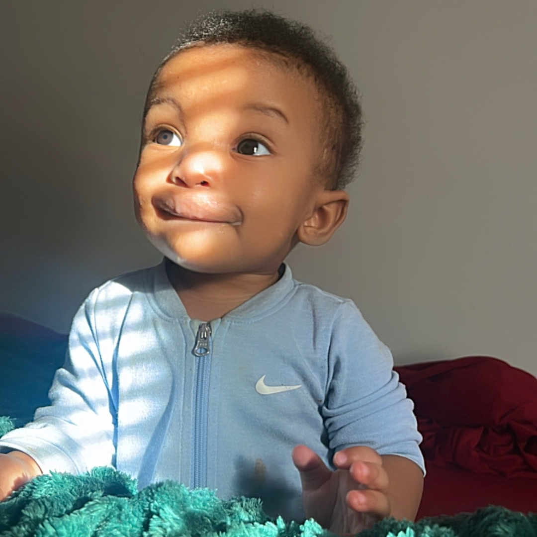 Brynden joined the competition — help win amazing prizes! baby, bed, blanket, child, clothing, cozy, curly_hair, cute, expression, face, fingers, hand, indoor, light, nike, portrait, shadow, smile, toddler, young