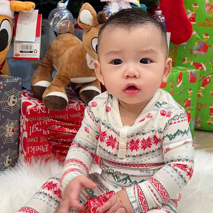 Jay joined the competition — help win amazing prizes! baby, child, christmas, christmas_tree, cute, decorations, festive, gift, holiday, holiday_season, indoors, pajamas, plush_toy, present, reindeer, sitting, smiling, stocking, white_rug, winter