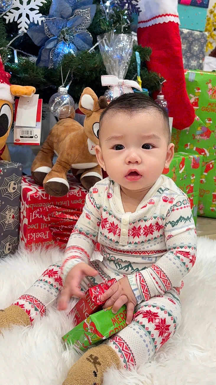 Jay joined the competition — help win amazing prizes! baby, child, christmas, holiday, pajamas, gift, present, plush_toy, reindeer, christmas_tree, stocking, decorations, festive, cute, sitting, white_rug, indoors, smiling, winter, holiday_season