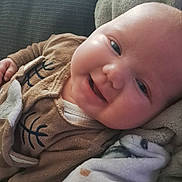 Ambre participe au concours pour gagner de l'argent avec cette photo : apparel, baby, blanket, brown_clothing, child, closeup, comfort, cozy, cute, face, happy, indoors, infant, lying_down, person, portrait, relaxed, smiling, soft_texture, warm