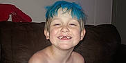 Hendrix joined the competition — help win amazing prizes! child, boy, smiling, blue_hair, missing_teeth, shirtless, indoor, couch, brown_couch, plush_toy, lobster_toy, wall_art, flower_painting, happy, freckles, face, hair, skin, portrait, living_room