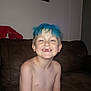 child, boy, smiling, blue_hair, missing_teeth, shirtless, indoor, couch, brown_couch, plush_toy, lobster_toy, wall_art, flower_painting, happy, freckles, face, hair, skin, portrait, living_room