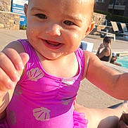 Eliza joined the competition — help win amazing prizes! toddler, child, swimsuit, purple, smiling, water_droplets, outdoor, poolside, sunlight, happy, person, baby, summer, fun, vacation, playful, water, daylight, people, clothing