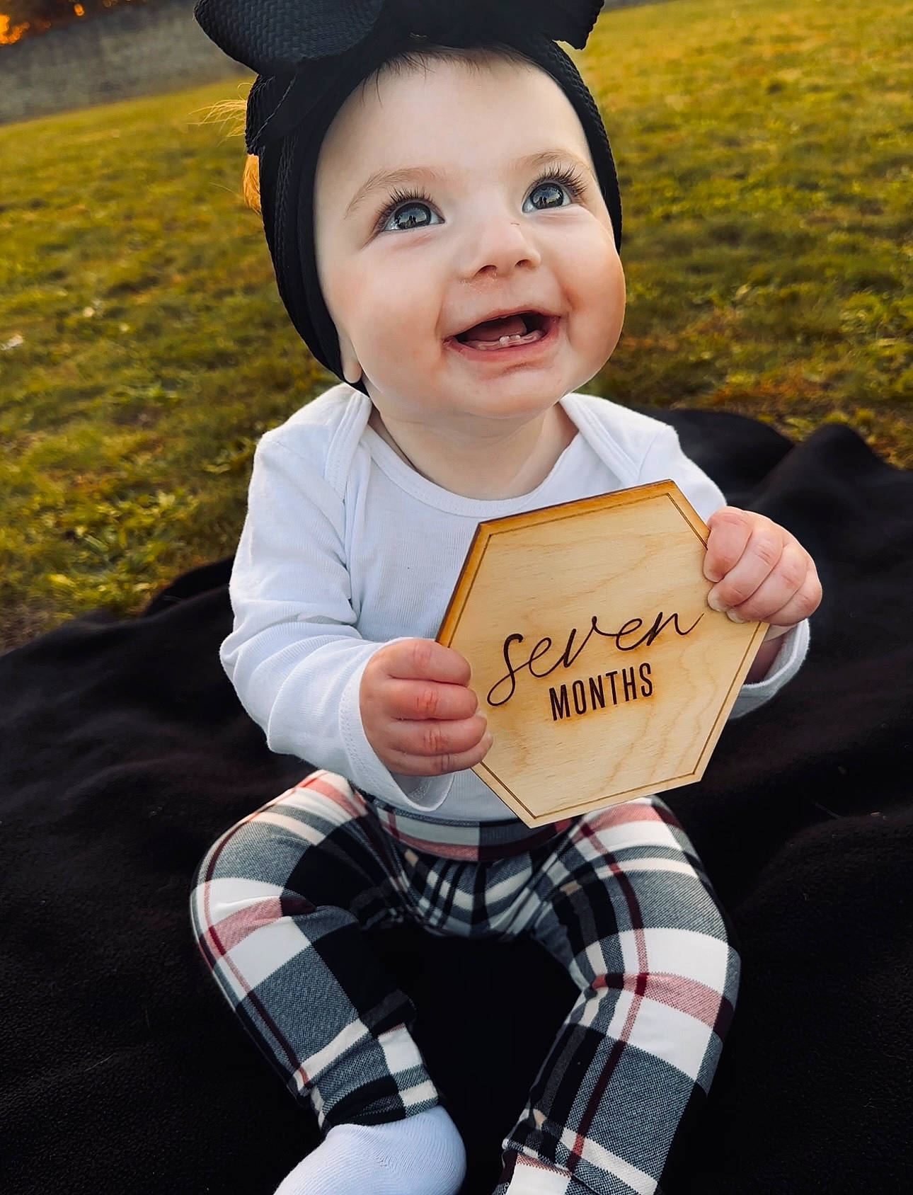Myli joined the competition — help win amazing prizes! baby, baby_toddler_clothing, child, costume_hat, event, flash_photography, fun, gesture, grass, happy, hat, joy, mortarboard, pattern, person, plaid, sitting, smile, sock, sun_hat