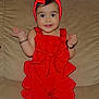 toddler, child, red_clothing, headband, bow, couch, smile, bracelet, indoors, happy, person, footwear, cute, standing, baby, accessory, playful, fashion, portrait, home