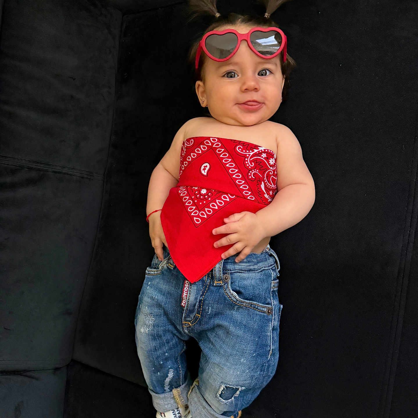 Lara a rejoint le concours — aidez-le/la à gagner de superbes lots ! accessories, baby, black_couch, casual_wear, child, cute, fashion, footwear, happy, indoor, jeans, person, pigtails, portrait, red_bandana, relaxed, smiling, socks, sunglasses, young_child