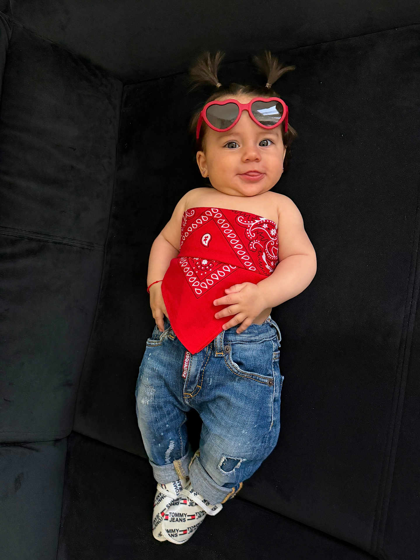 Lara a rejoint le concours — aidez-le/la à gagner de superbes lots ! baby, child, sunglasses, red_bandana, jeans, socks, pigtails, black_couch, cute, smiling, fashion, casual_wear, indoor, portrait, person, happy, young_child, accessories, footwear, relaxed