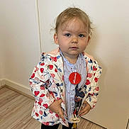 Livya participe au concours pour gagner de l'argent avec cette photo : accessory, casual, child, clothing, expression, face, floor, footwear, hair, heart_pattern, indoor, jacket, looking_at_camera, pacifier, person, standing, toddler, toy, wall, young_child