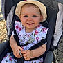 toddler, child, smiling, stroller, hat, floral_dress, sun_hat, happy, outdoor, baby, cute, clothing, person, seatbelt, hands, toy, daylight, face, young_child, baby_accessory