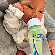 Julian is registered to the contest to win money with this photo: baby, infant, bottle, feeding, dr_browns, white_clothing, hand, face, closeup, newborn, person, soft_fabric, skin, eyes, mouth, nurturing, caring, indoors, cute, sleepy