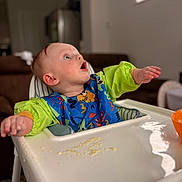 Jaxson is registered to the contest to win money with this photo: baby, infant, high_chair, bib, messy, meal_time, food_on_tray, surprised, looking_up, home_interior, living_room, couch, bowl, orange_bowl, plastic_tray, green_sleeves, portrait, cute, feeding, puree